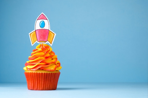 写真 スタートアップロケットで飾られたホイップクリームとカップケーキ