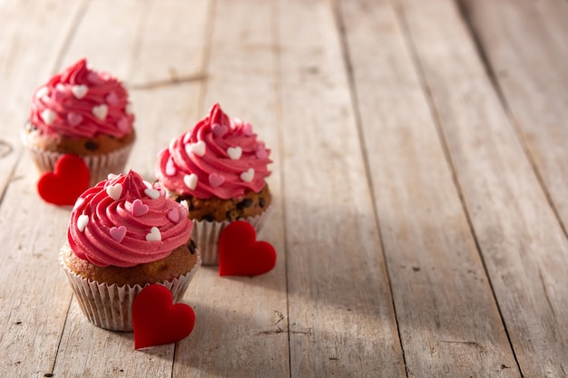 Cupcakes decorated with sugar hearts for Valentine's Day on wooden table