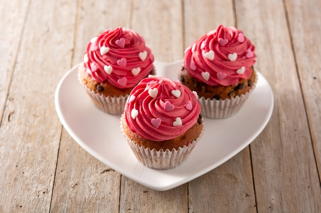 cupcakes decorated with sugar hearts for valentine's day on wooden table