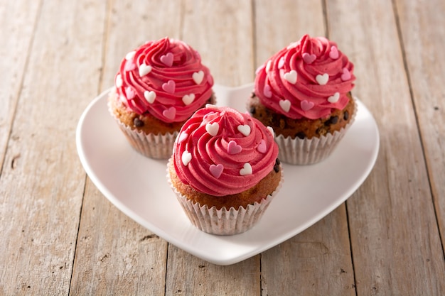 Cupcakes decorated with sugar hearts for Valentine's Day on wooden table