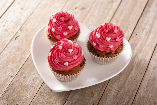 Cupcakes decorated with sugar hearts for Valentine's Day on wooden table