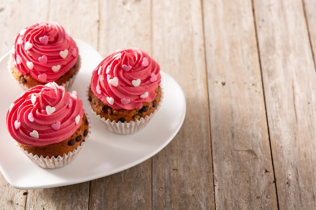 Cupcakes decorated with sugar hearts for Valentine's Day on wooden table