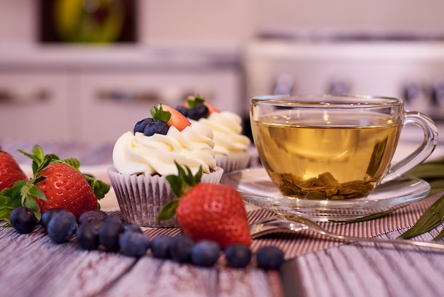 Cupcakes met aardbeien en bosbessen. Cupcakes met een kopje thee.