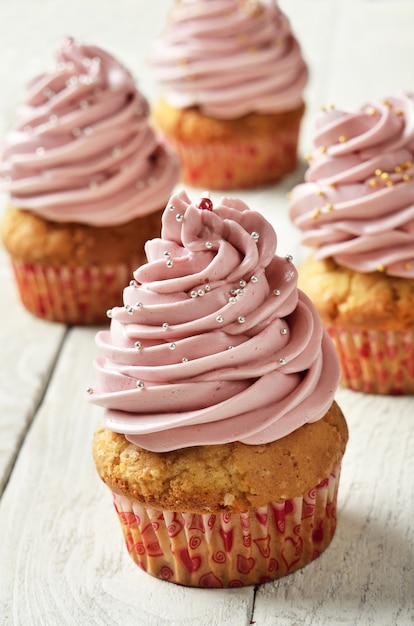 Cupcakes met roze room gedecareerd met zilveren en gouden ronde hagelslag