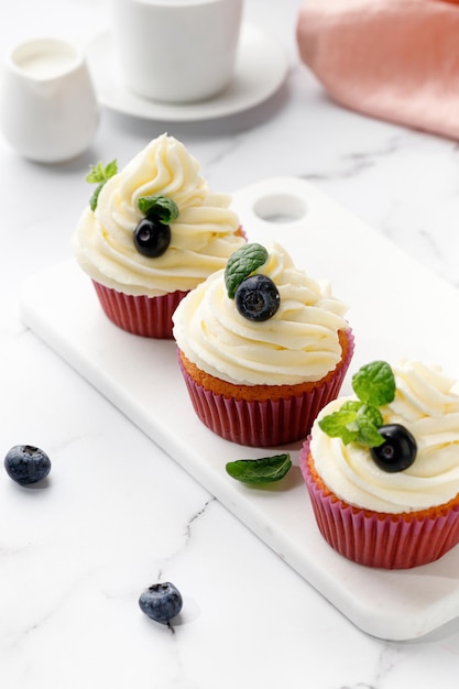 Foto cupcakes muffin decorati con crema di bacche e foglie di menta verde delizioso dolce fatto in casa