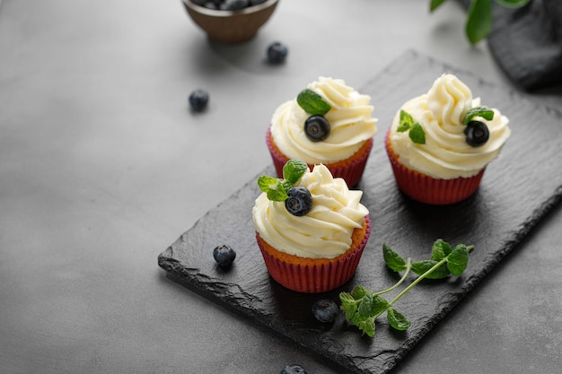 Photo cupcakes muffins decorated with cream on dark slate cutting board delicious homemade dessert pastry