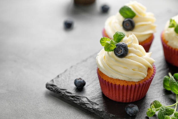 Cupcakes muffins decorated with cream on dark slate cutting board Delicious homemade dessert Pastry