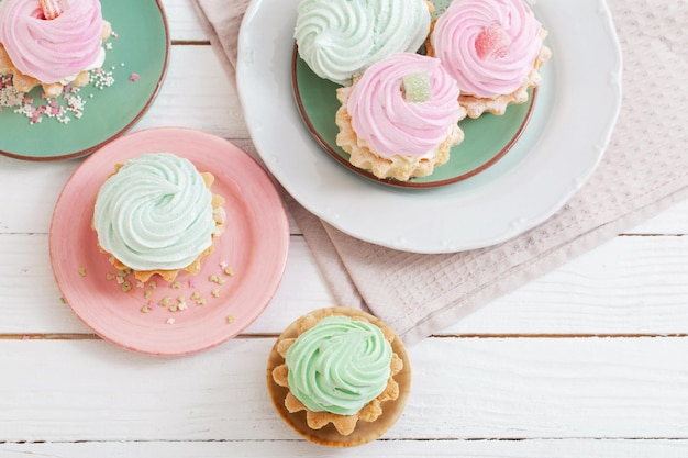 Cupcakes on plates on white wooden background