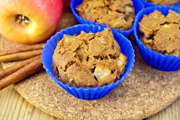 Cupcakes rogge met appel in siliconen mallen, appels, kaneel op een houten planken achtergrond