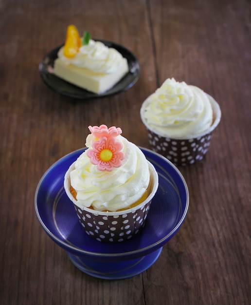 Cupcakes served in polka dot paper mould with buttercream frosting put on wood background