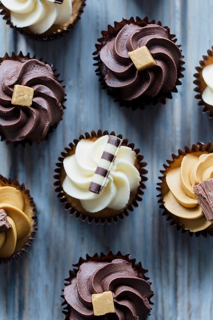 Cupcakes versierd met chocoladekaramel en vanillesuikerglazuur op een houten ondergrond