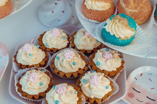 Cupcakes with beige cream decorated with a pink caramel flower and colorful pastry beads