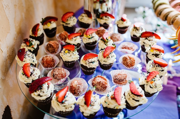 Cupcakes with cream and strawberries. Cake, Pie, Fruit cakes, muffins, nuts on a glass surface on the plate. Dessert. The sweetness.