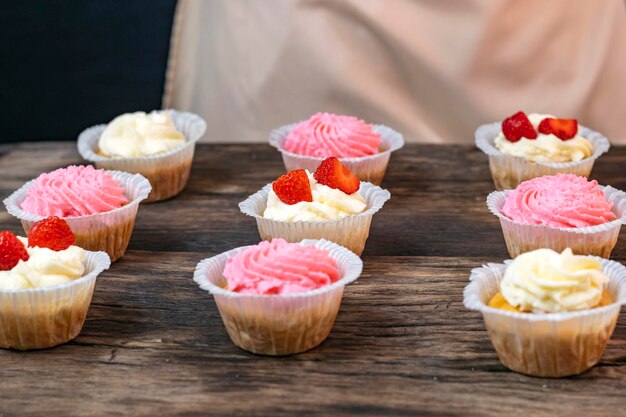 Cupcakes with cream and strawberries Homemade vanilla muffins on wooden table