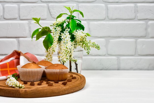 cupcakes on a wooden board with a bouquet of white flowers three cupcakes on a blackboard with a tablecloth and a bouquet of flowers on a white wooden table place for an inscription