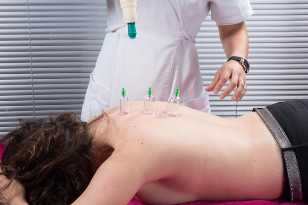 Cupping therapy spa woman doctor removes cups from the patient's back