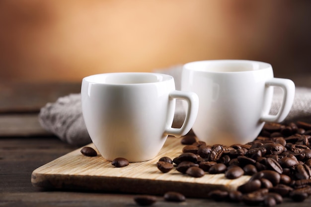 Cups of coffee and beans on blurred background