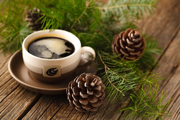 Tazze di caffè accanto a coni e un ramo di pino