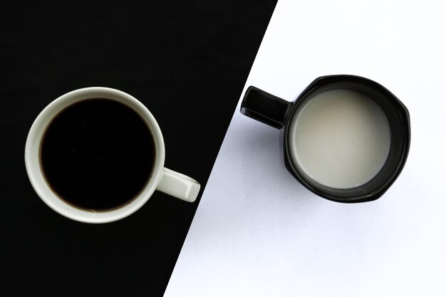 Cups of coffee and milk on black and white background