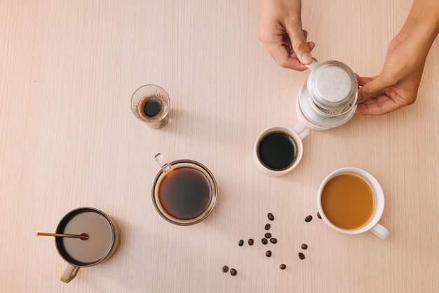 Cups of coffee with coffee beans and vietnamese Phin filter on wooden background