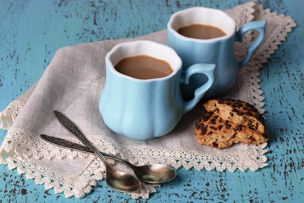 Cups of coffee with cookies and napkin on wooden table