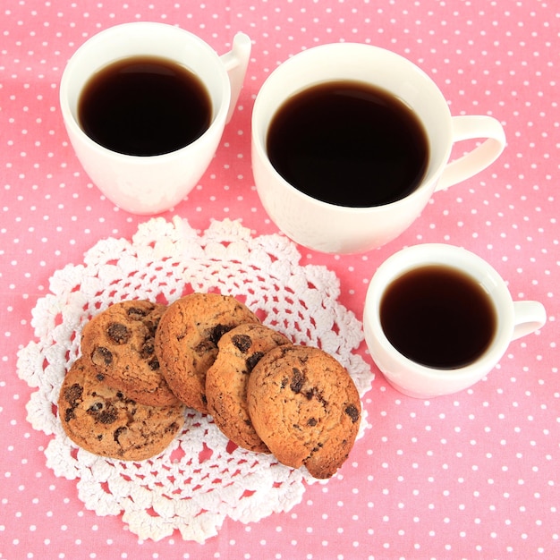 Cups of coffee with cookies on pink napkin