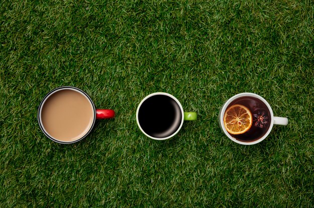 Cups of coffee with espresso and cappuccino and cup of tea on green grass