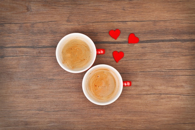 Cups of coffee with hearts on wooden table