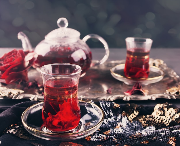 Cups of hot red karkade tea with teapot on the tray