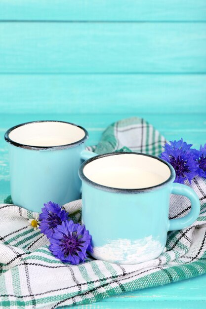 Cups of milk and cornflowers on wooden table