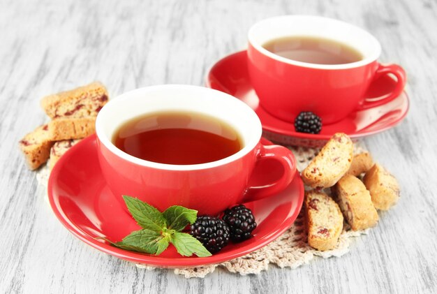 Cups of tea with cookies and blackberry on table closeup