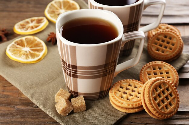 Cups of tea with cookies on table close-up