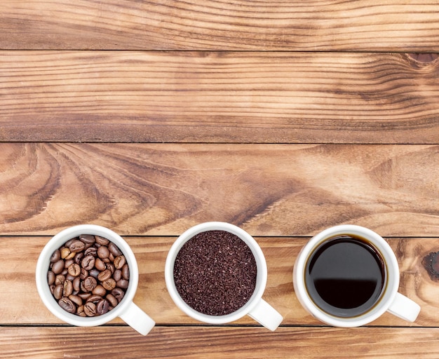 コーヒーを飲むカップ木製の背景に粉されたコーヒーと豆を飲むトップビューテキストのスペース