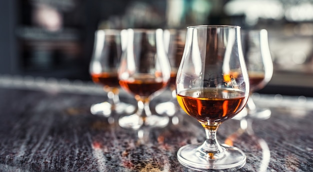 Cups with a cognac rum brandy or whiskey drink on a bar counter in night club.