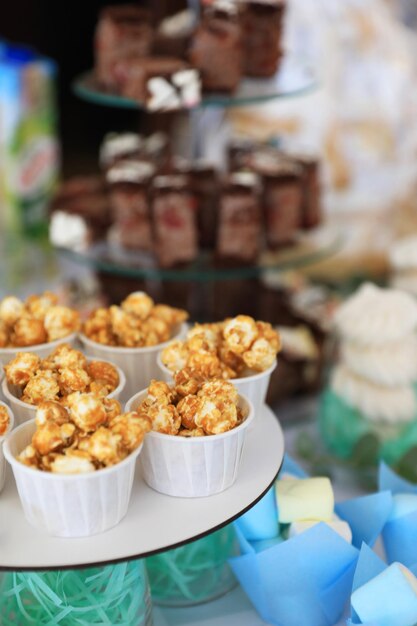 Cups with delicious caramel popcorn on dessert stand