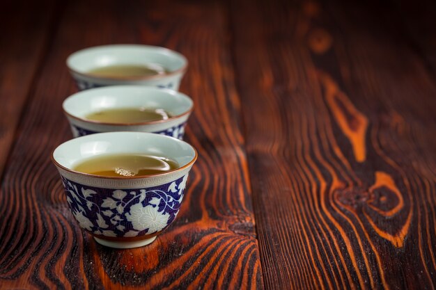 Cups with green tea on wood