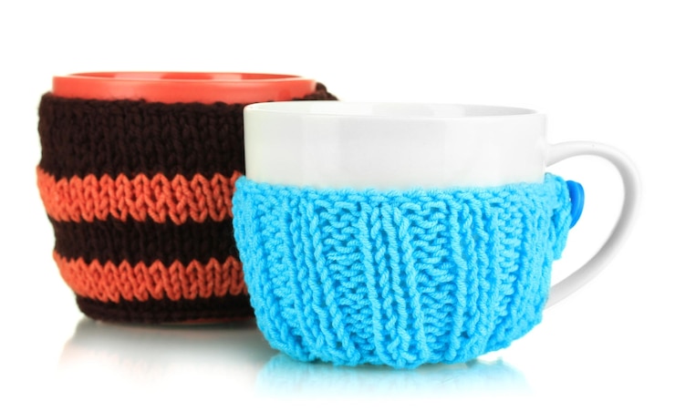 Photo cups with knitted things on it isolated on white