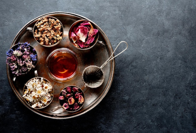 Cups with medicinal dried herbs and herbal tea on a tray top view Healing herbs