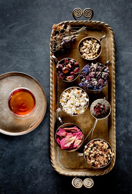 Tazze con erbe medicinali essiccate su un vassoio e vista dall'alto di tisane erbe curative