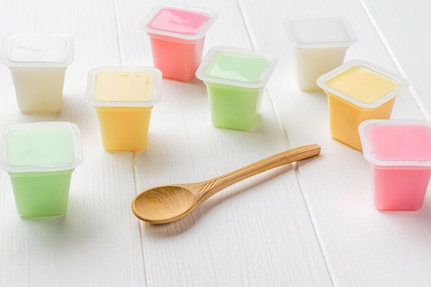 Cups with multicolored yogurts on a white wooden table. Natural healthy food. Fruit and milkshakes.