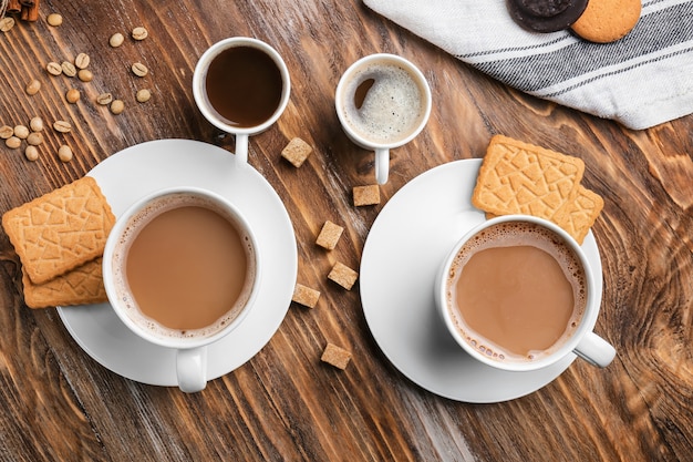 Cups with tasty aromatic coffee and cookies on wooden table