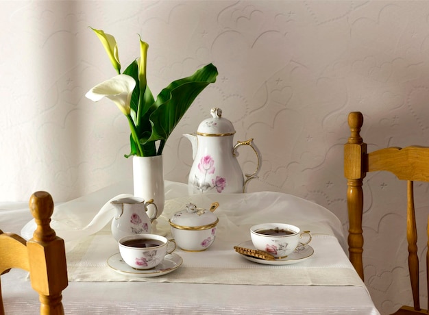 Photo cups with tea cookies and a bouquet of callas on the table closeup