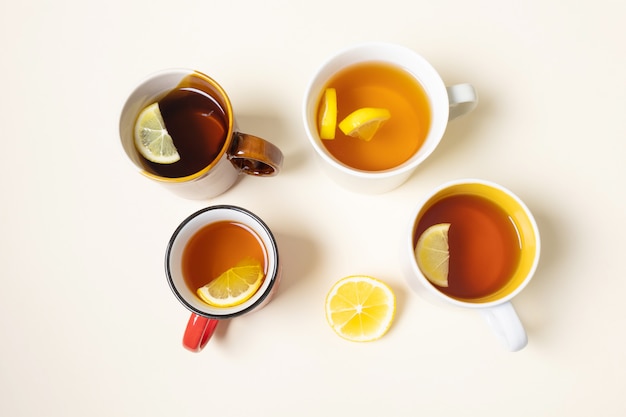 Чашки с чаем с лимоном на бежевом фоне.