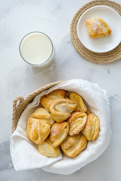 Biscotti di ricotta in un cesto, su un tavolo bianco con il latte. concetto di colazione. biscotti ai fiocchi di latte.