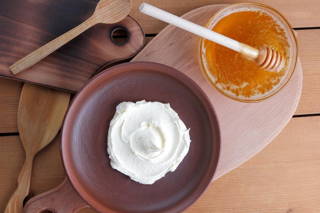 Curd mass on a clay plate on a wooden board Still life with cheese and honey on a wooden black background Closeup