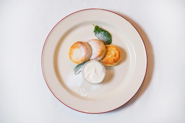 Сырники со сметаной, украшенные сахарной пудрой и мятой Концепция вкусного сытного домашнего завтрака в ресторане