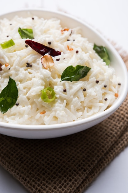 Curd Rice or Dahi Bhat OR Chawal with curry leaf, peanuts and chilli- Served in a bowl over moody background. Selective focus