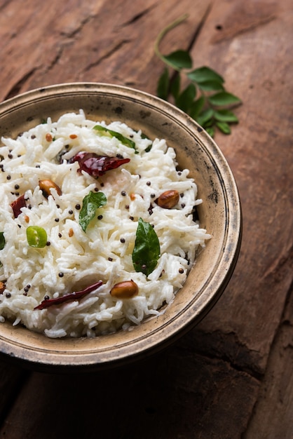 Curd Rice or Dahi Bhat OR Chawal with curry leaf, peanuts and chilli- Served in a bowl over moody background. Selective focus