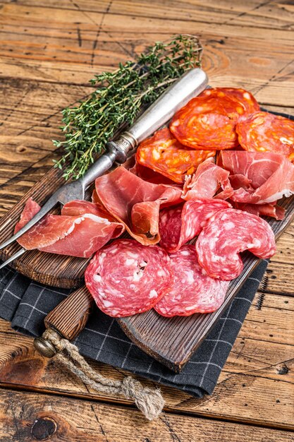 硬化肉の盛り合わせは、伝統的なスペインのタパスとして使用されました。木の板にサラミ、ハモン、チョリソソーセージ。木製の背景。上面図。