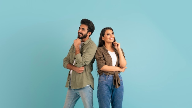 Curious eastern couple looking at copy space touching chin